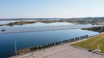 A photo of Alqueva solar offshore plant that shows a part of the solar pannels on top of the body of water on a clear and sunny day