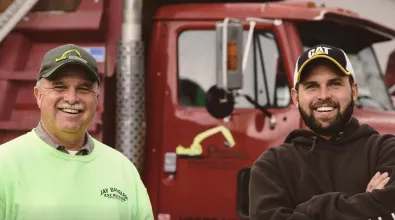two man wearing caps and smiling in from of a red truck